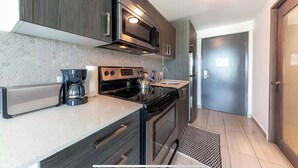 A modern kitchen with dark wooden cabinets, stainless steel appliances, and a hexagonal tile backsplash.