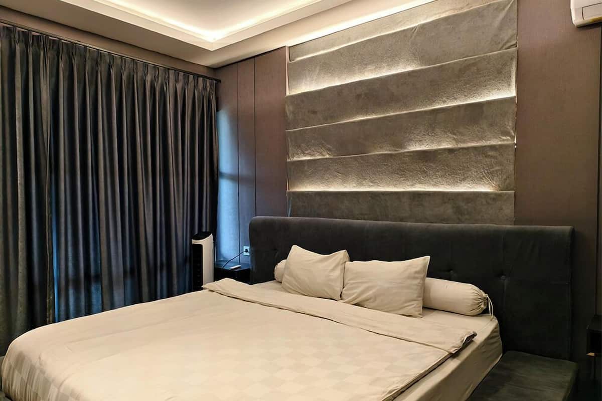 A modern bedroom with a large bed, dark headboard, and a wall-mounted light fixture.