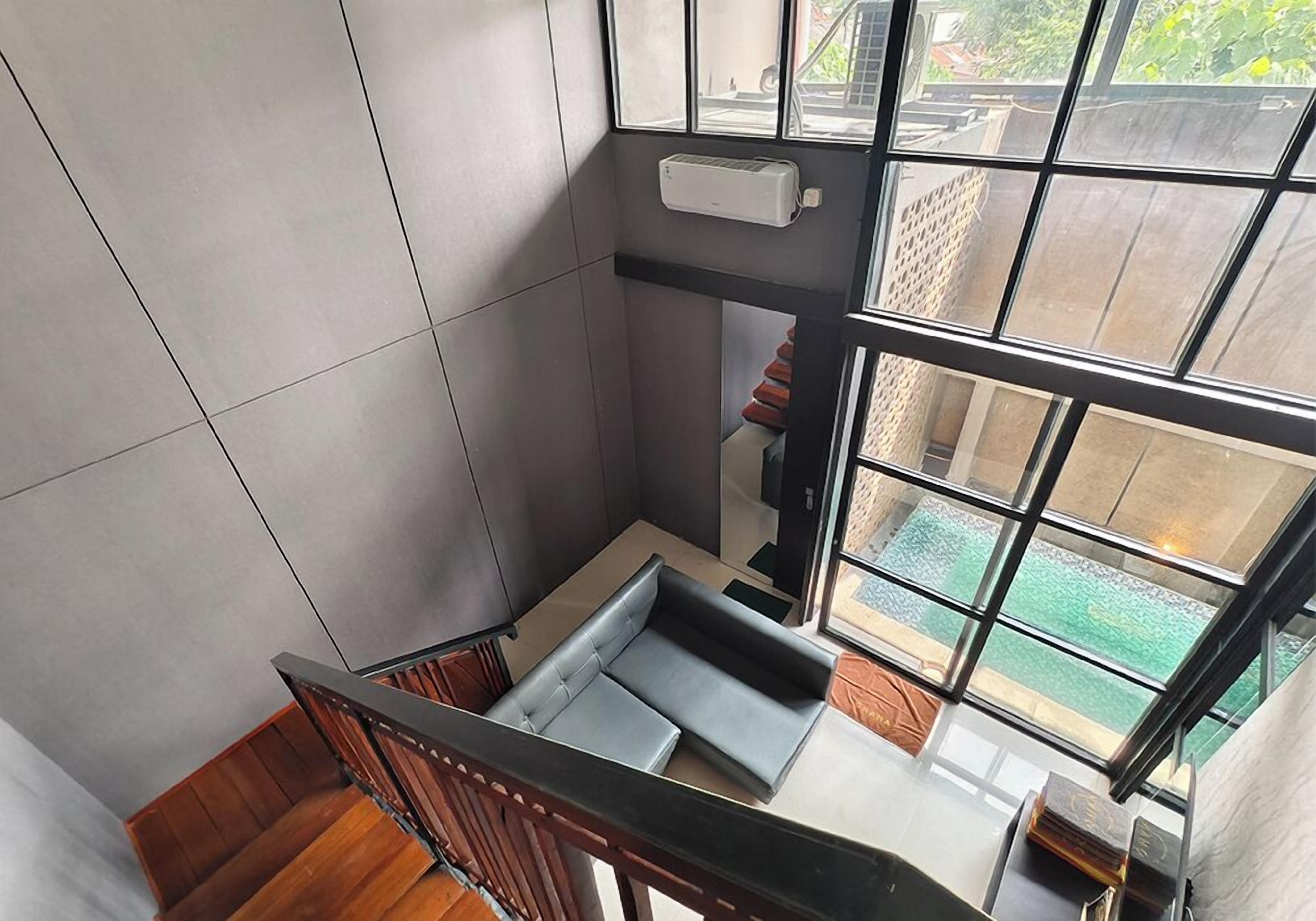 A modern interior with a staircase, a built-in bench, and large windows offering a view of the outdoors.