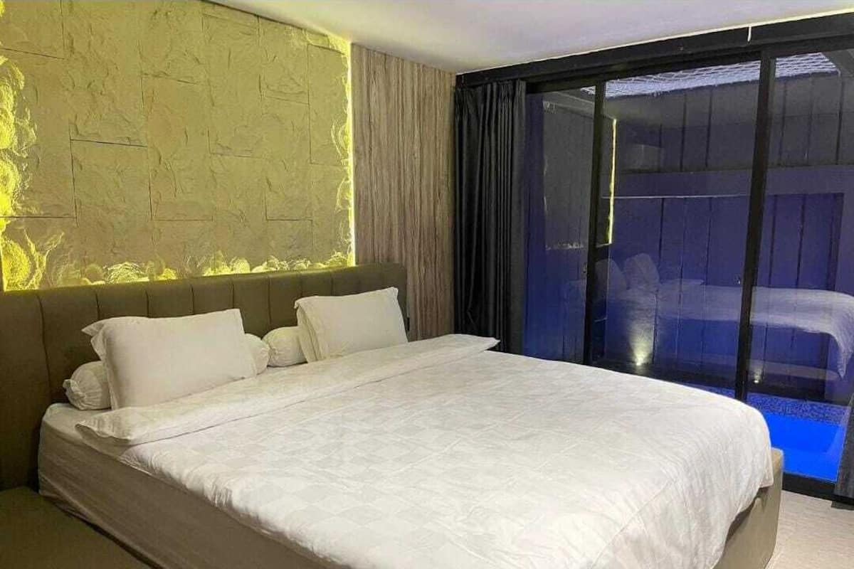 A modern bedroom with a large bed, a headboard, and a view of a balcony.