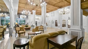 A spacious lobby with high ceilings, chandeliers, and classical architecture.