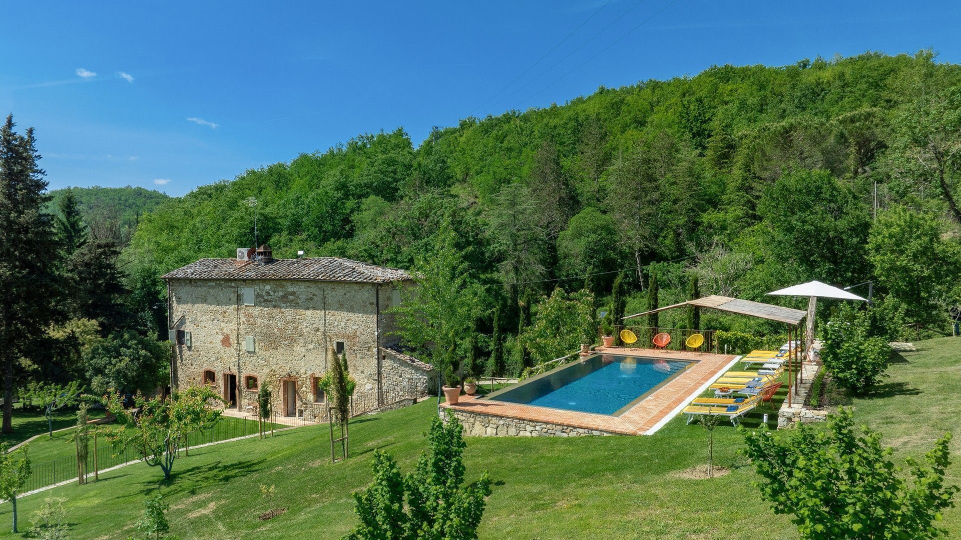 A stone villa with a swimming pool and outdoor seating.