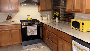 A kitchen with wooden cabinets, a stainless steel stove, a microwave, and a window with blinds. - 3 Bedroom Merrillville Escape, quiet, rural w/ shopping centers, spacious (Merrillville)
