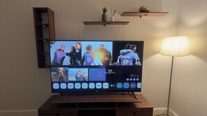 Un televisor de pantalla plana montado en un soporte de madera con un estante superior.