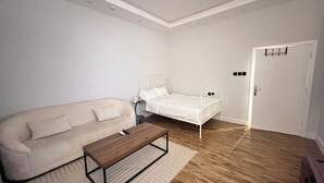 Un dormitorio con cama, sofá, mesa de centro y puerta con interruptor de luz.