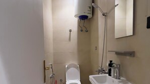 Un baño pequeño y moderno con inodoro, lavamanos y calentador de agua montado en la pared.