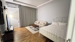 Una habitación de hotel moderna con cama, sofá, televisión y escritorio.