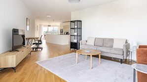 A modern living room with a grey sofa, a wooden coffee table, and a TV on a wooden cabinet. - Blueground | Alt-Wiedikon, balcony, nr Uetliberg (Zurich)