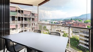 A balcony with a table and chairs, overlooking a cityscape with buildings and mountains. - Blueground | Alt-Wiedikon, balcony, nr Uetliberg (Zurich)