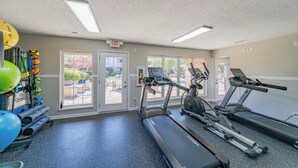 Un gimnasio con cintas de correr, pelotas de ejercicio y una máquina de ejercicios fijada a la pared.