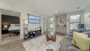 Una sala de estar moderna con una cama, un televisor, un comedor y una cocina.
