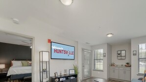Amplia sala de estar con una cama, un televisor y un letrero que dice "WELCOME TO HUNTSVILLE".
