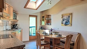A modern kitchen with a skylight, wooden cabinets, and a dining area with a round table and chairs.