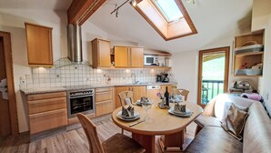 A compact kitchen with wooden cabinets, a built-in oven, and a dining area with a wooden table and chairs.