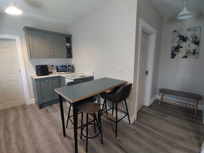 A compact kitchen with a microwave, a small dining table, and bar stools. - Apartment - Sleeps 4 - Near Aran Islands - Parking (Galway)