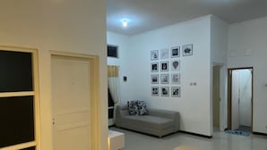 A modern living room with a dining table, sofa, and wall-mounted lights. - Omah Kulon Malioboro (Kasihan)