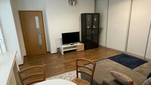 Un salon avec un téléviseur, des meubles en bois et un meuble de rangement.