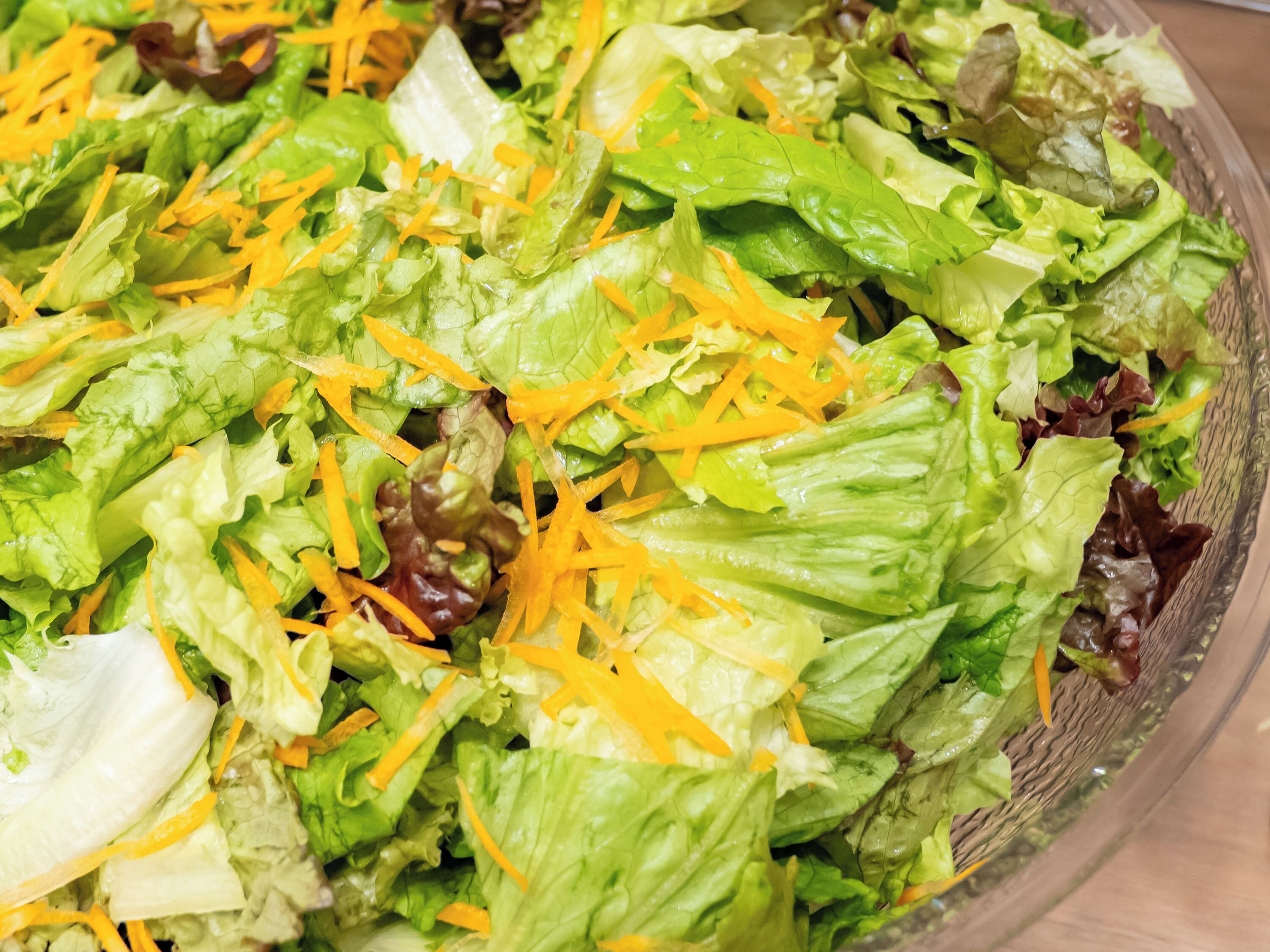 A close-up of a salad with mixed greens and shredded carrots.