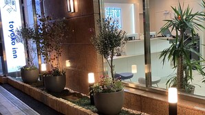 A hotel entrance with a sign reading 'Toyoko Inn,' potted plants, and a reception desk. - Toyoko Inn Tokyo Minowa eki (Tokyo)