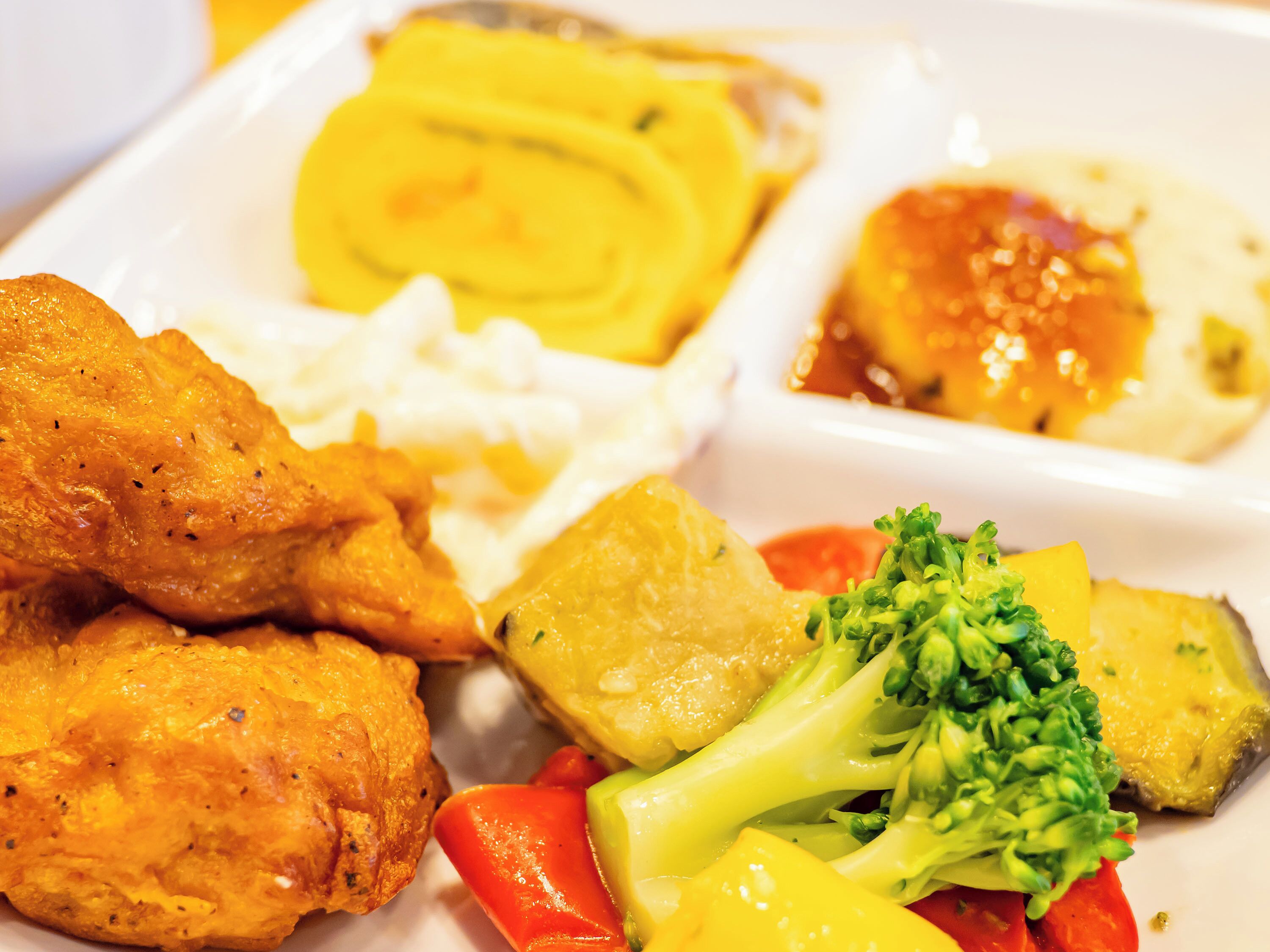 A plate with fried chicken, mashed potatoes, and a side of vegetables including broccoli and bell peppers.
