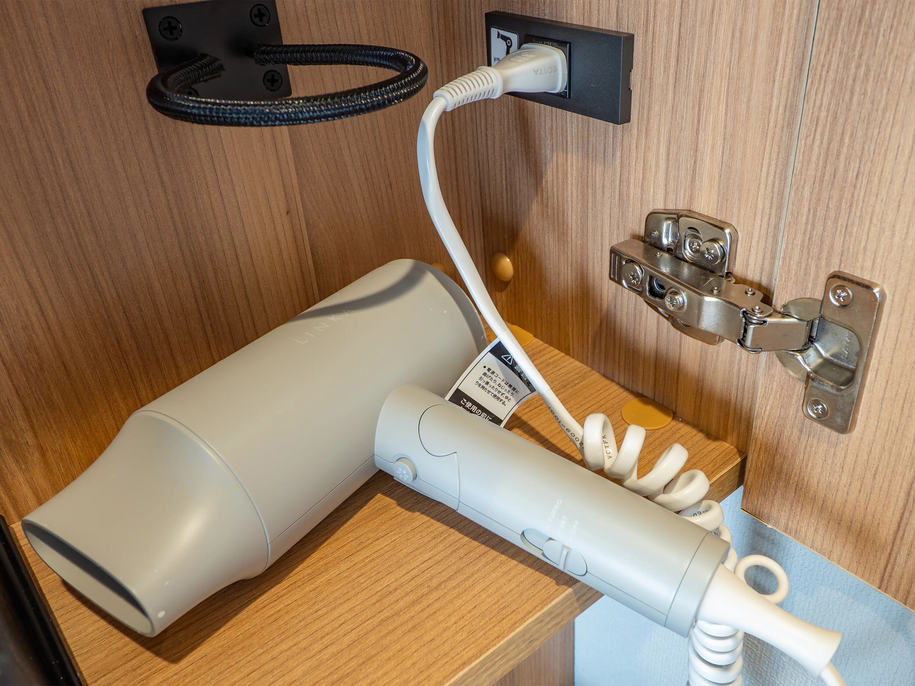 A hairdryer and a power strip mounted on a wooden wall.