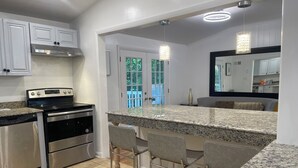 Une cuisine moderne dotée de plans de travail en granit, d’appareils électroménagers en acier inoxydable et d’un coin bar avec des tabourets.