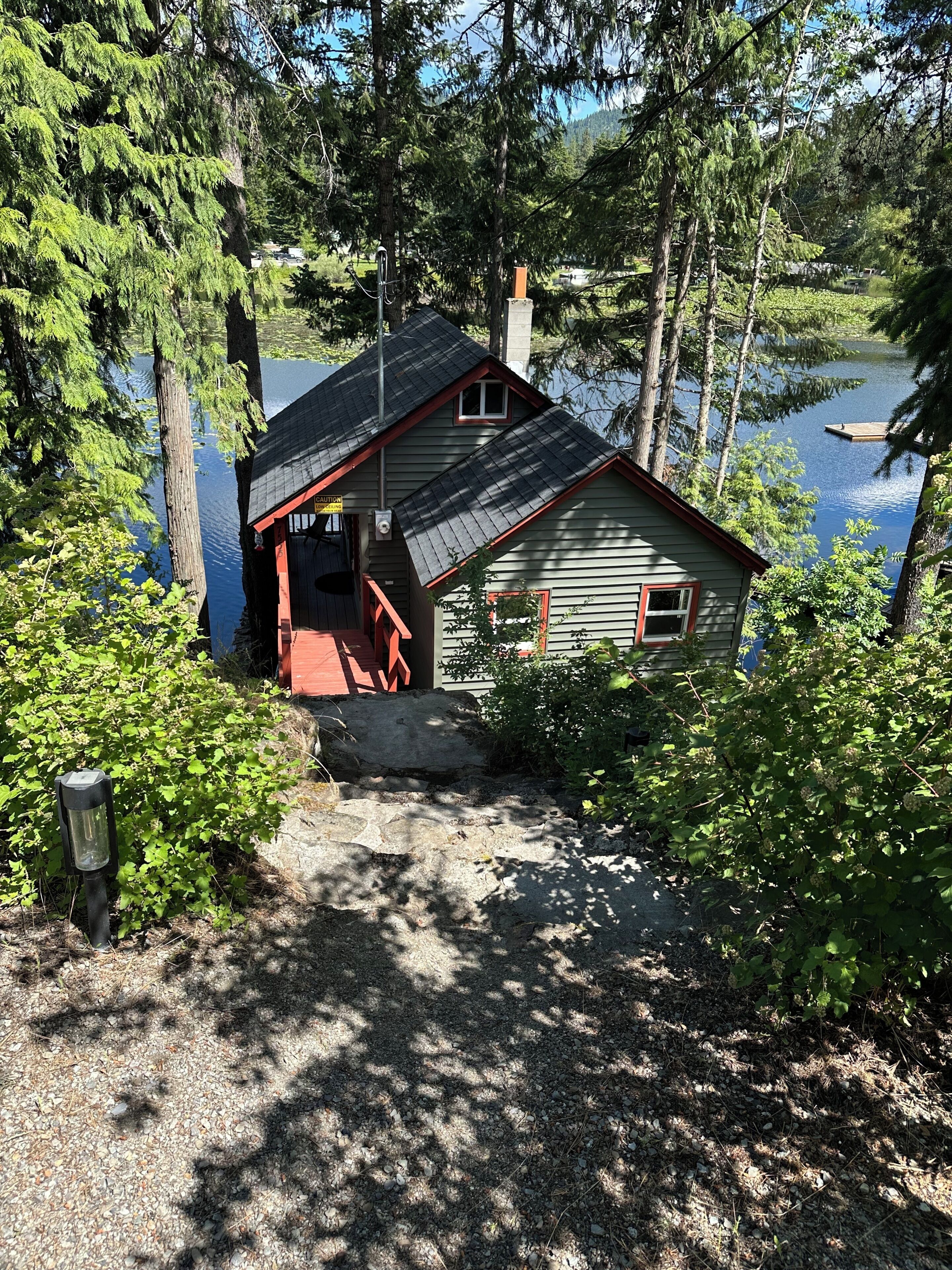 A cabin with a dock, surrounded by dense forest and a lake.