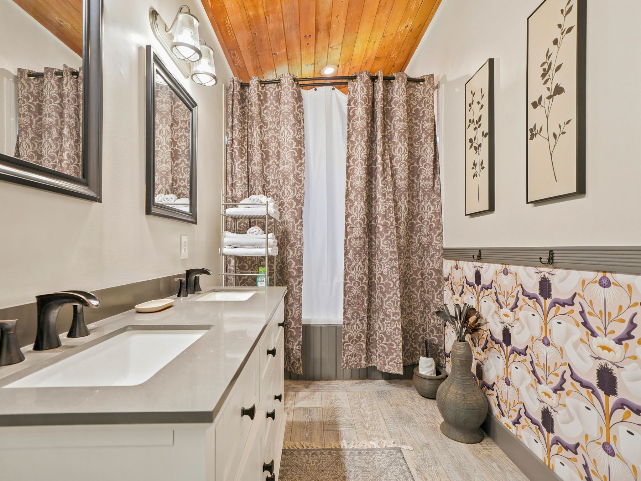 Une salle de bain avec deux lavabos, un miroir, un porte-serviettes et un rideau de douche.