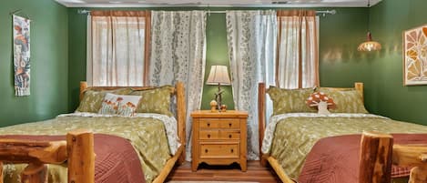 A room with two beds, a wooden nightstand, a lamp, and a ceiling fan.