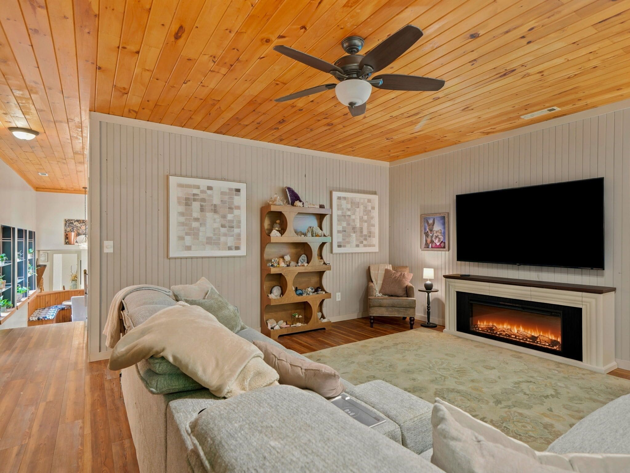 Una sala de estar con chimenea, ventilador de techo y televisor de pantalla plana.