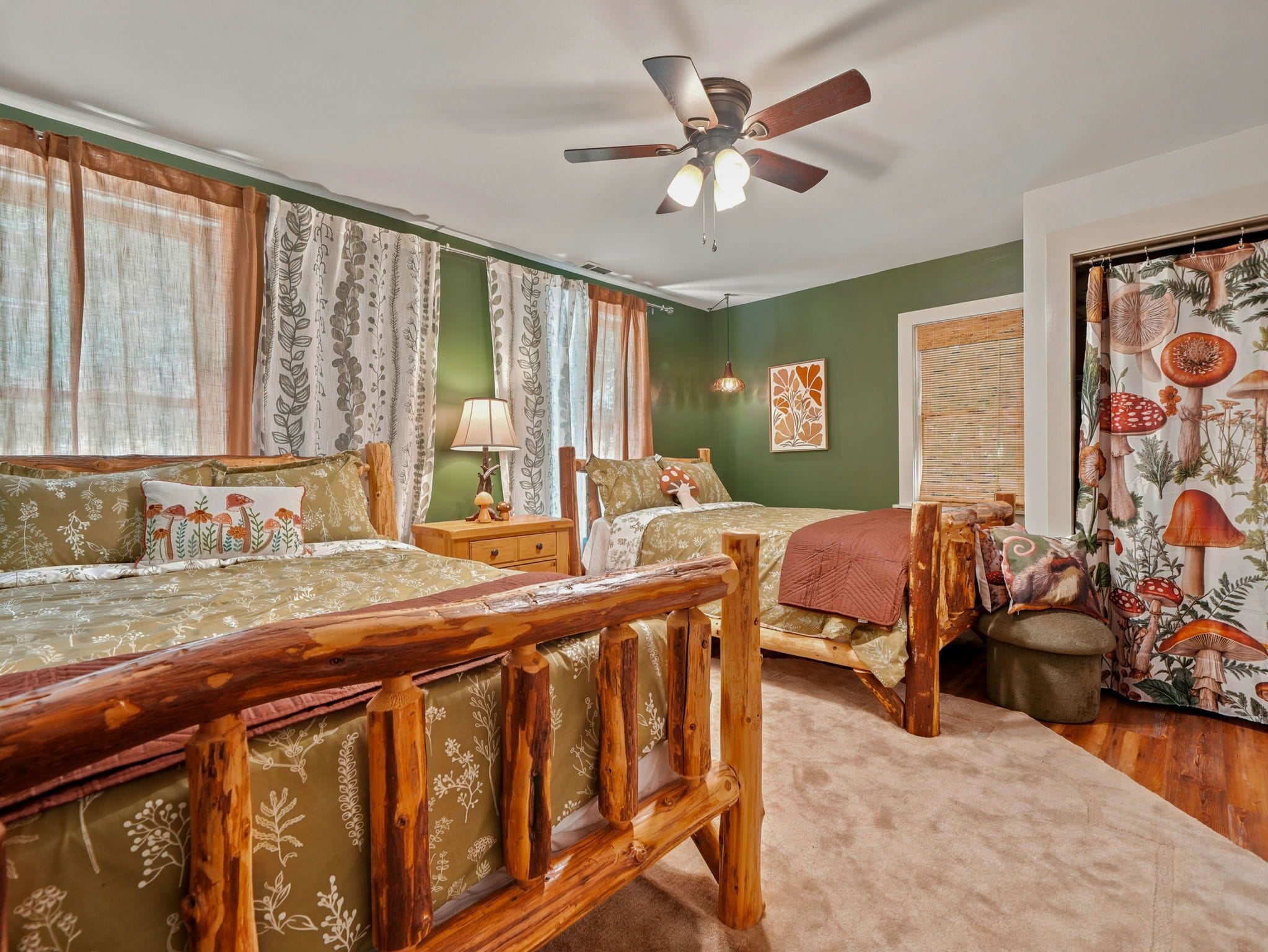 A bedroom with two beds, a ceiling fan, and a window with curtains.