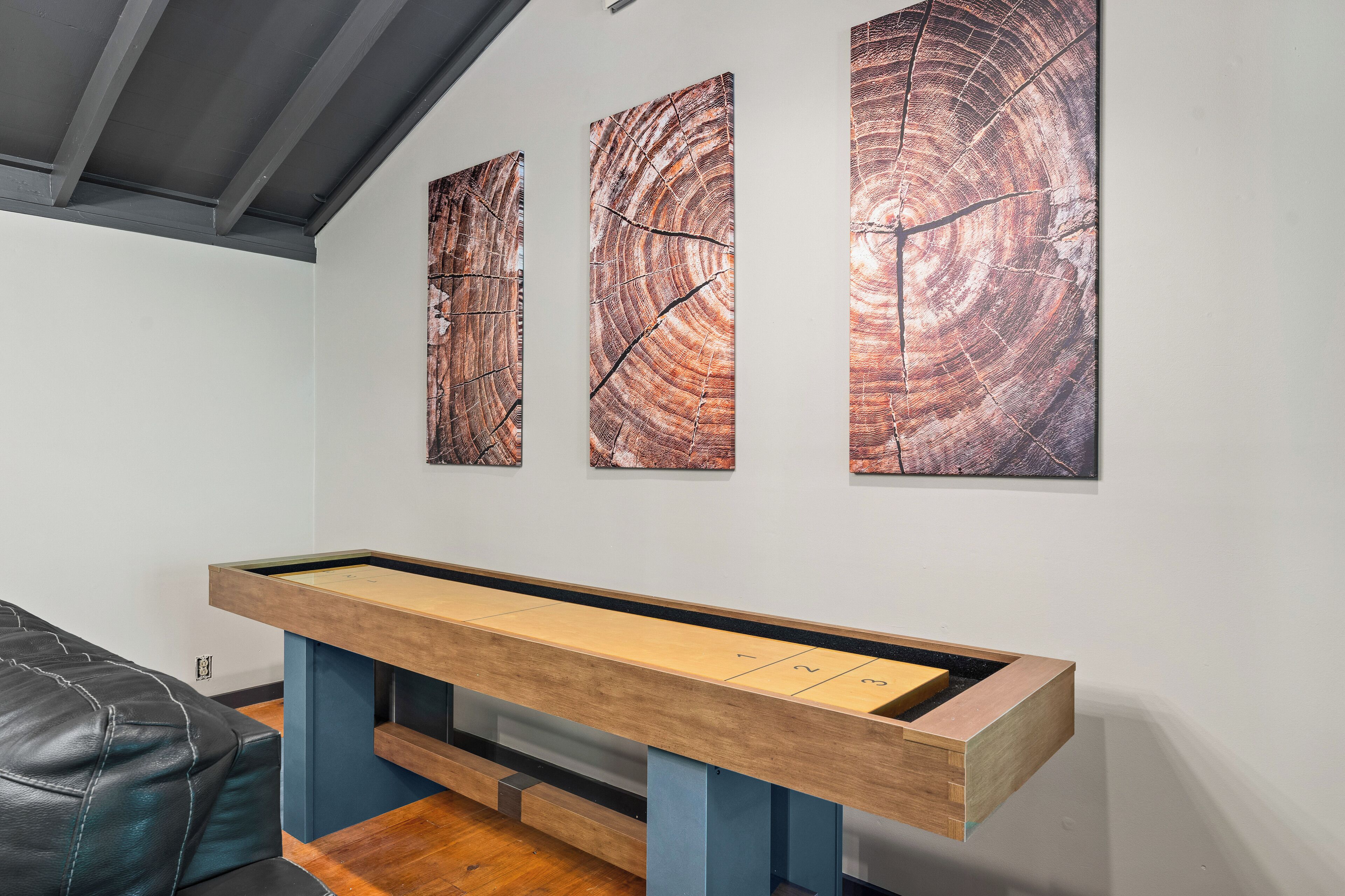 A billiards table with numbered pockets, a leather couch, and three abstract paintings on the wall.