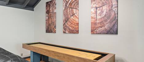 A billiards table with numbered pockets, a leather couch, and three abstract paintings on the wall.