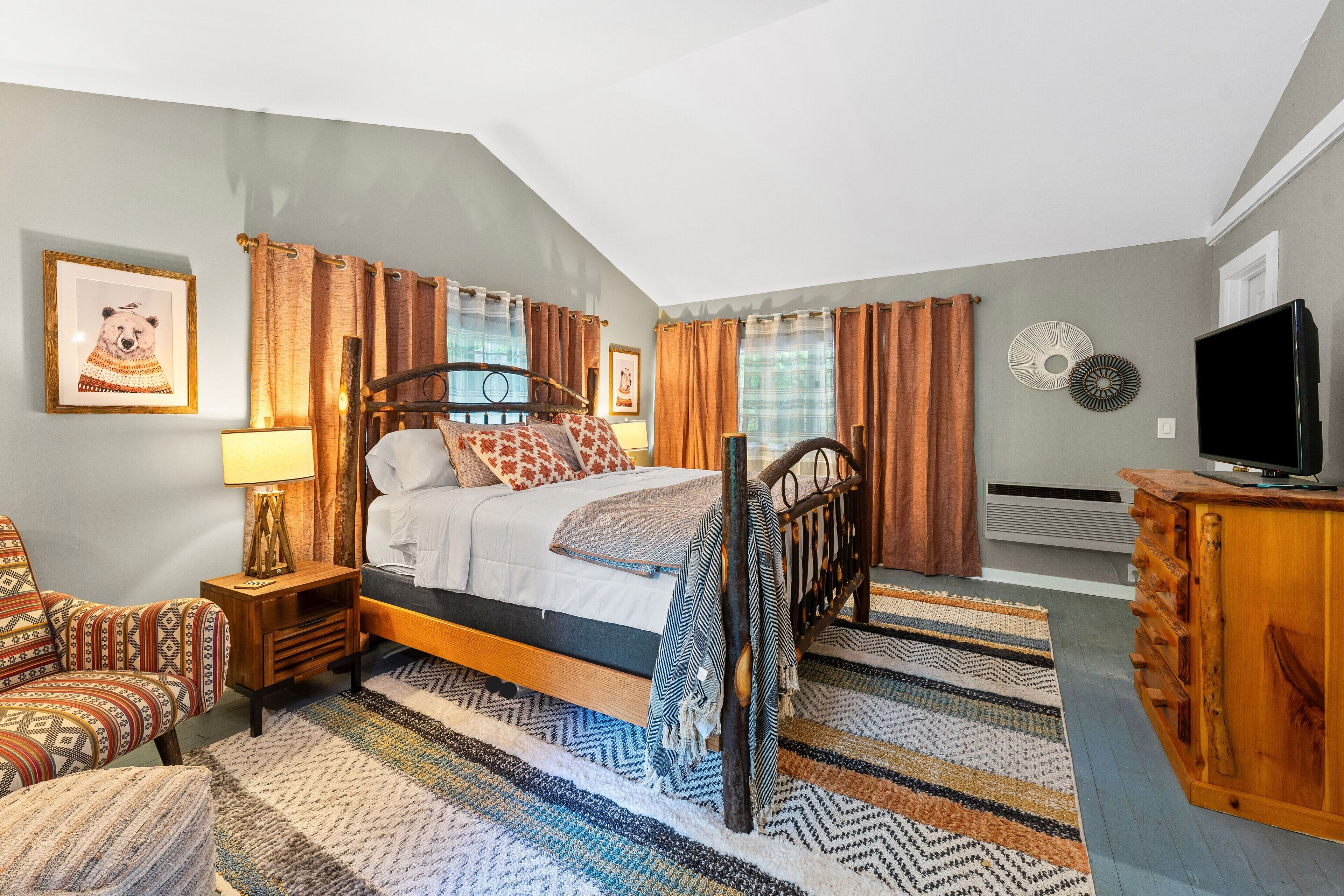 Une chambre à coucher avec un lit, une chaise, une commode et un téléviseur.