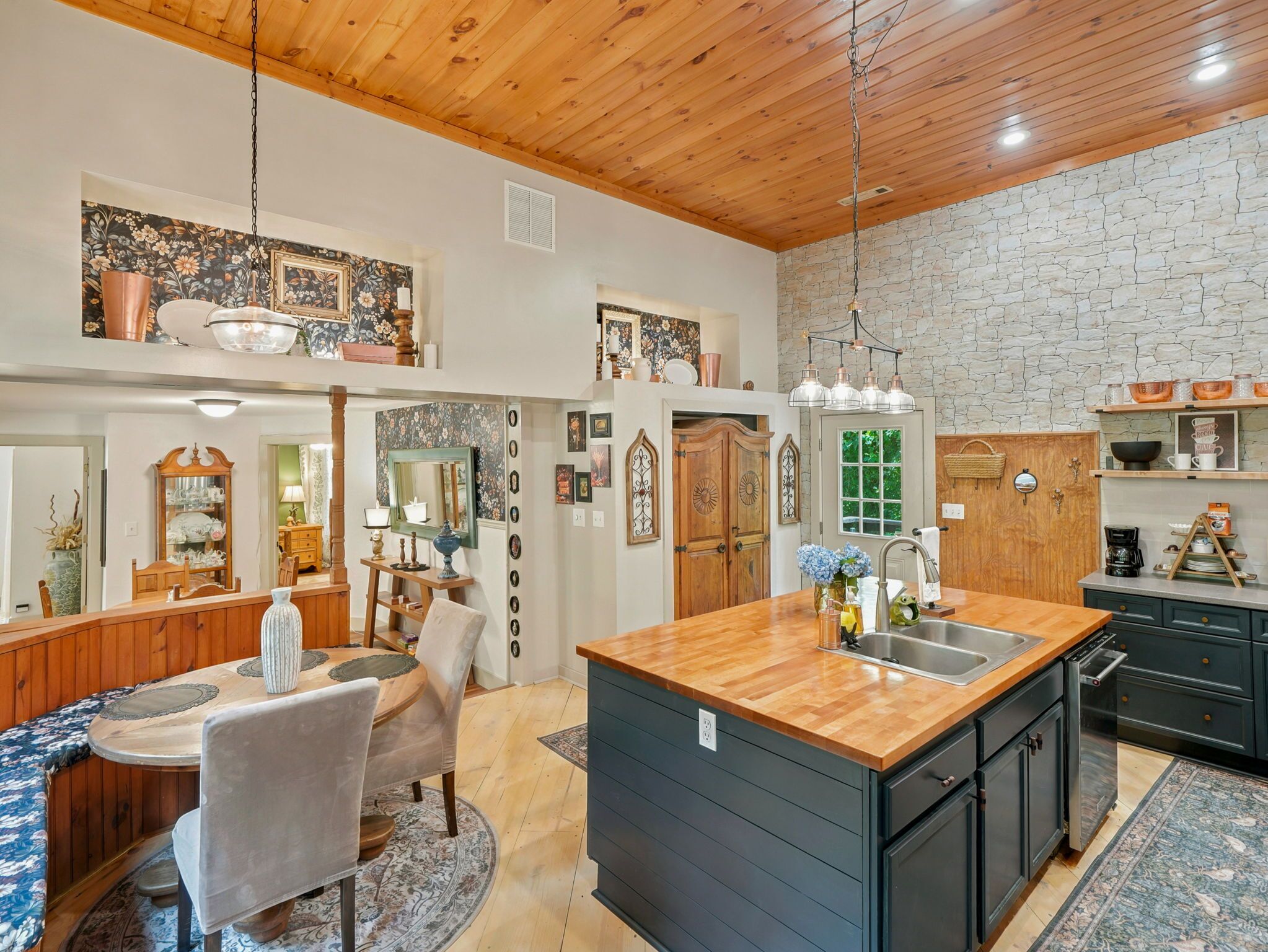 A spacious kitchen with a central island, wooden cabinets, and a stone accent wall.