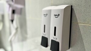 Baño con dos dispensadores de gel antibacterial fijados a la pared.