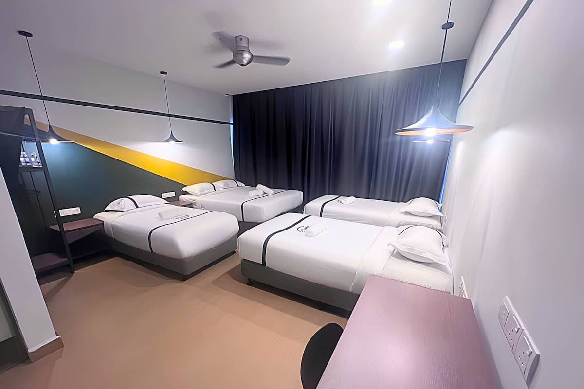 Habitación de hotel con dos camas individuales, escritorio, ventilador de techo y minibar.