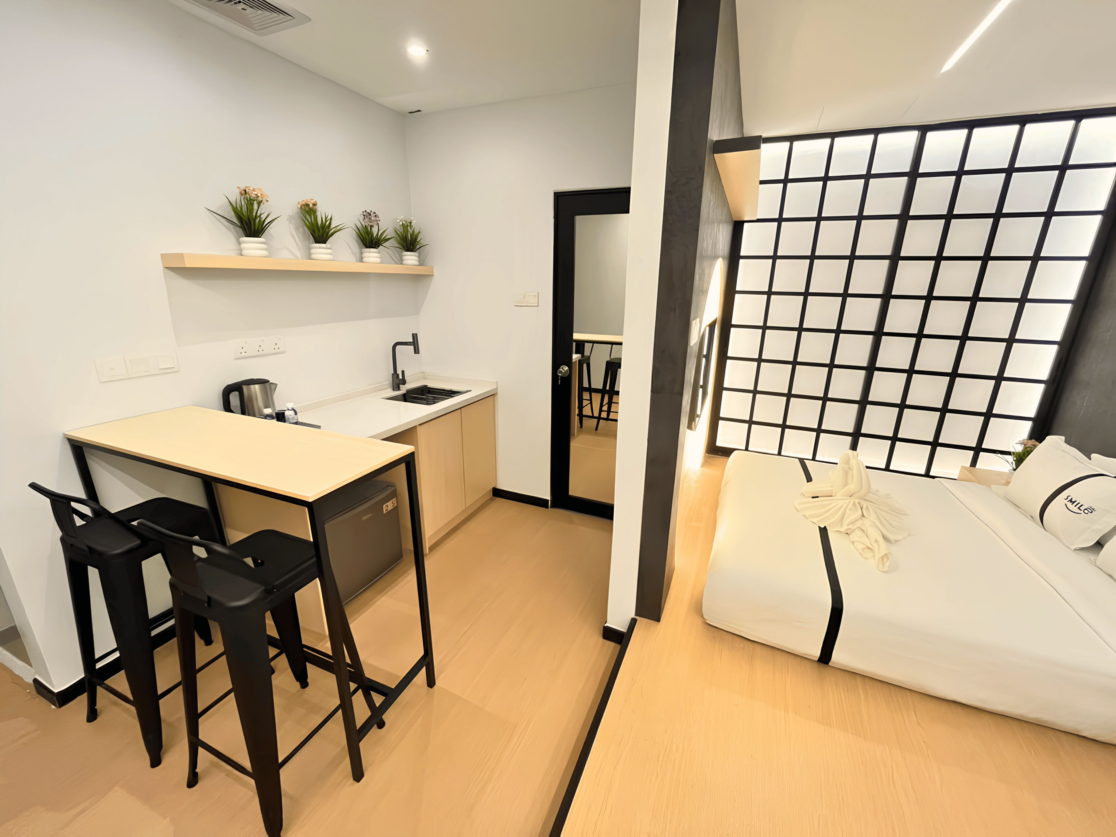 Una cocina moderna con comedor, un refrigerador pequeño y un sofá con un cojín decorativo.