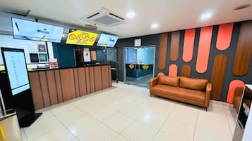 A reception area with a reception desk, a brown sofa, and a wall with abstract patterns.