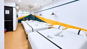 Habitación de hotel con tres camas, una puerta negra, un cartel que dice 'Lo siento' y un cartel de 'No estacionar'.