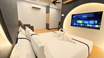A modern hotel room with a bed, a flat-screen TV mounted on the wall, a ceiling fan, and an air conditioning unit.