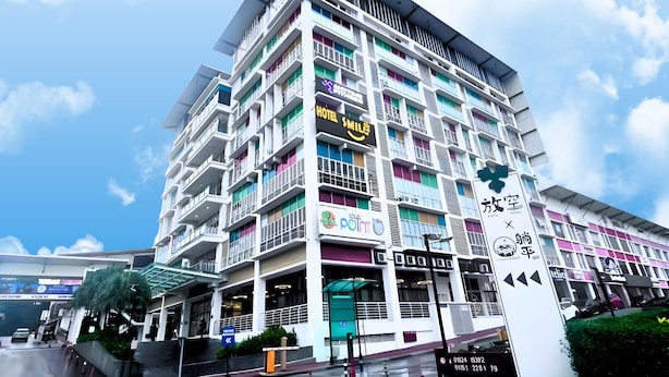 Un hotel de varios pisos con balcones, una terraza en la azotea y señalización diversa que indica servicios y comodidades.
