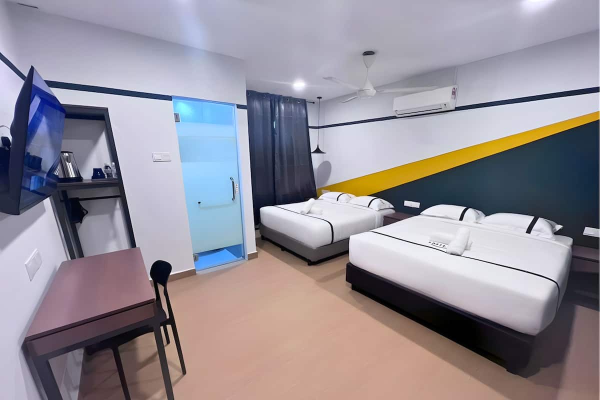 Habitación de hotel con dos camas, un escritorio, una silla, un armario y un ventilador de techo.