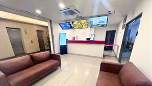 Un área de recepción con mostrador, televisor y dos sofás.