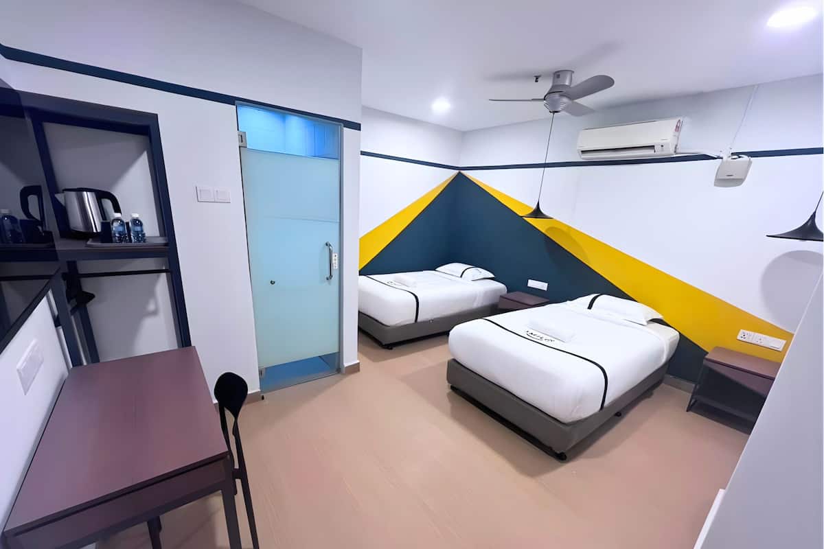 Habitación de hotel con dos camas, un escritorio, una silla, un armario y un ventilador de techo.
