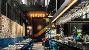 A modern restaurant with a bar area, seating arrangements, and a decorative wall.