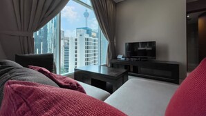 A modern hotel room with a large window, a flat-screen TV, and a comfortable seating area.