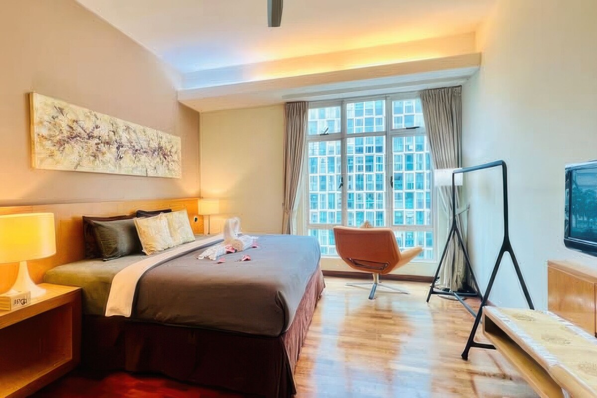 Habitación de hotel con cama, escritorio, silla, televisor y ventana con cortinas.