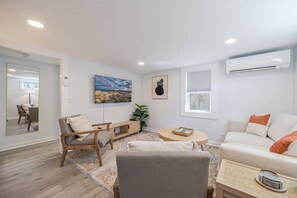 Ett vardagsrum med en soffa, en fåtölj, ett soffbord, en tv och konstverk på väggen.