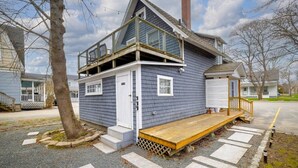 Une maison à deux étages avec un porche à l’avant, une petite terrasse et un garage.